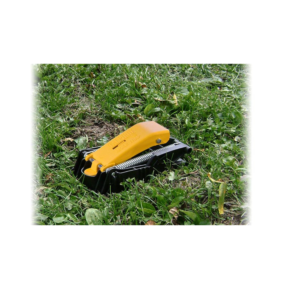 Talpirid MT4150 mole trap shown set in soil, demonstrating low-profile placement, yellow foot pedal and reusable glass-filled nylon construction