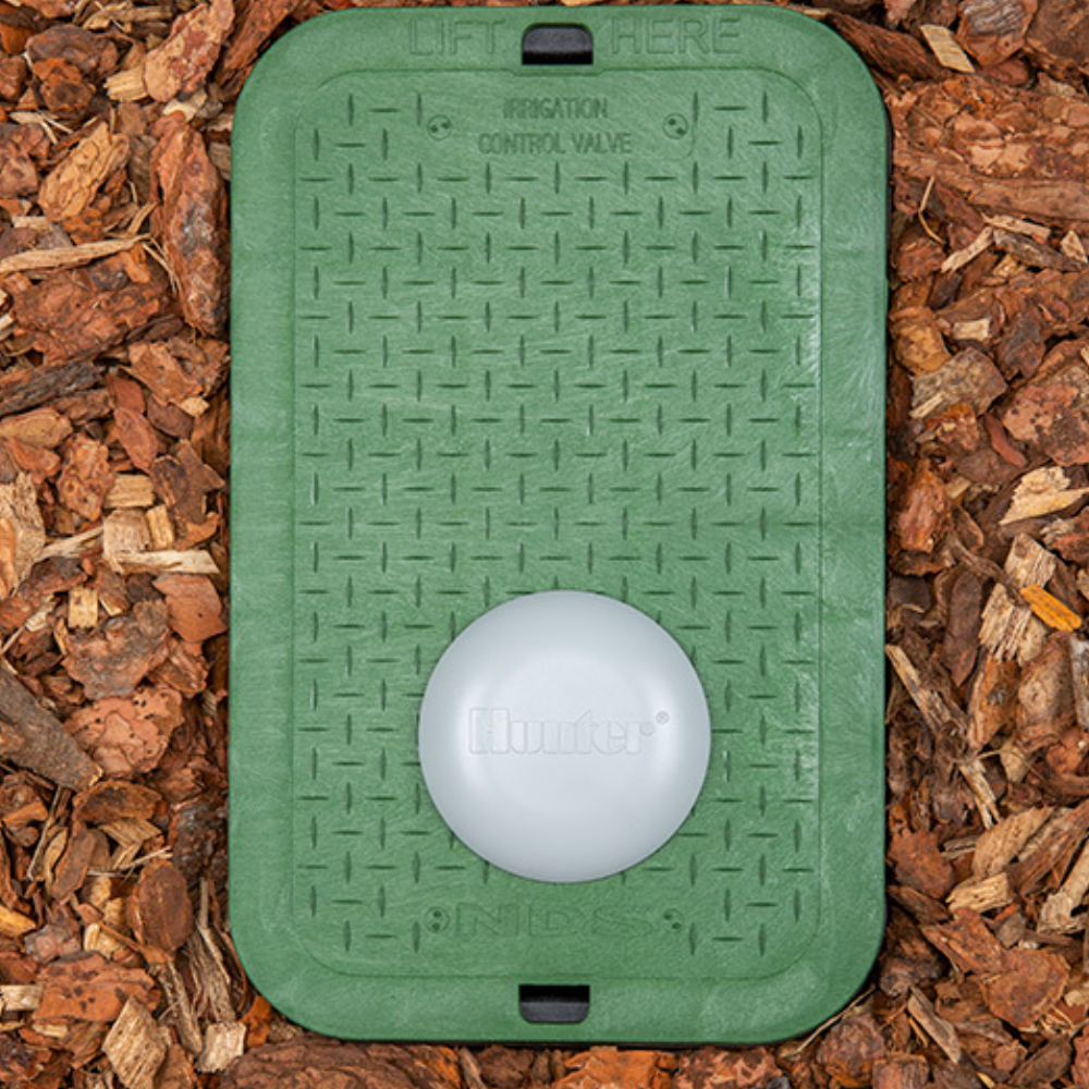 Illustration of Hunter Wireless Valve Link mounted on valve box lid with antenna and nearby irrigation valves, demonstrating wireless connectivity and placement (approx. 100 characters).