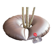 Front view of a brown TreeGator Junior Pro 15-gallon watering bag wrapped around a young tree trunk, showing the fill opening and straps, outdoors.