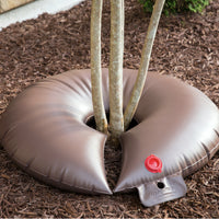 Image of the TreeGator Junior Pro 15-gallon bag on a landscaped bed, illustrating scale next to low branches and surrounding mulch.