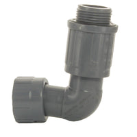 White 1-inch PVC manifold elbow photographed at an angle showing the female inlet and valve-side NUT x MVCONN connection, used for irrigation manifolds.