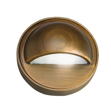 Kichler 15477CBR Centennial Brass 12V solid cast brass deck light with etched lens and low-voltage leads, shown installed on a wooden deck