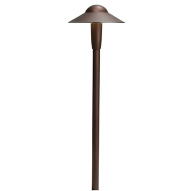 Kichler 6-inch dome LED path light in textured architectural bronze installed along a garden pathway, showing shade and stake