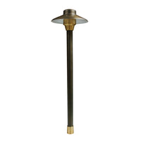 Centaurus 6-inch low-voltage path light on an 18-inch brass riser, weathered brass finish, frosted cylindrical glass lens.