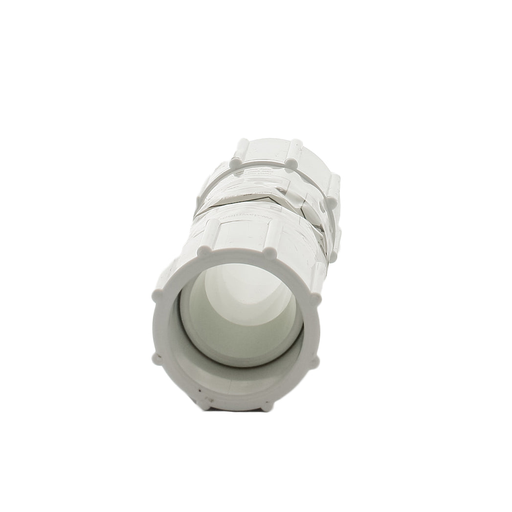 Side view of Dawn KRC429-010 KwikRepair coupling installed beside a 1-inch PVC pipe, illustrating compact collapsed and extended sleeve lengths.