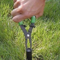 Close-up of Rain Bird PTC-1 pull-up tool showing flat-tipped handle for cap access and jaws holding a pop-up stem.