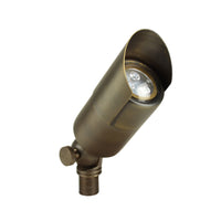 Unique Valor up light in weathered brass finish showing the fixture head, tempered glass lens, knuckle and mounting stake installed in landscape setting